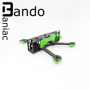 Peut inclure: Cadre de drone noir et vert avec le texte "Bando maniac" en noir. Le cadre présente un design en fibre de carbone avec des accents verts sur les bras et le dessus. Le cadre du drone est conçu pour construire un drone personnalisé.