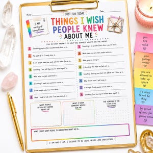 May include: A white paper worksheet titled Things I Wish People Knew About Me on a gold clipboard. The sheet features sixteen numbered prompts, three blank boxes for reflection, and colorful text. It includes affirmations on small sticky notes.