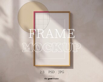 May include: A gold frame mockup with a white background and the text "FRAME MOCKUP" in white letters. The frame is on a light beige surface.