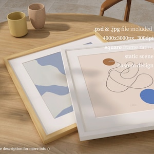 May include: Two framed abstract art prints on a wooden table. The print on the left has a blue and white abstract design. The print on the right has a brown and blue abstract design with a black line drawing. The text on the print reads "static scene custom design".
