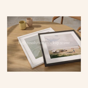 May include: Two framed photographs on a wooden table. The photo on the left shows a beach scene with waves crashing on the shore. The photo on the right shows a beach scene with people and tents. The photos are in white and black frames.