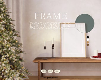 May include: A wooden frame mockup with a white background, sitting on a wooden table with two candlesticks and a Christmas tree in the background. The text "FRAME MOCKUP" is written in white on the wall behind the frame.