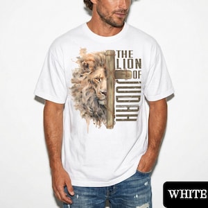 K&ouml;nnte beinhalten: Wei&szlig;es T-Shirt mit einem L&ouml;wenkopf- und Kreuz-Design. Der Text lautet "THE LION OF JUDAH". Die M&auml;hne des L&ouml;wen ist mit braunen und beigen Farbt&ouml;nen detailliert. Das Design ist auf ein wei&szlig;es T-Shirt gedruckt.