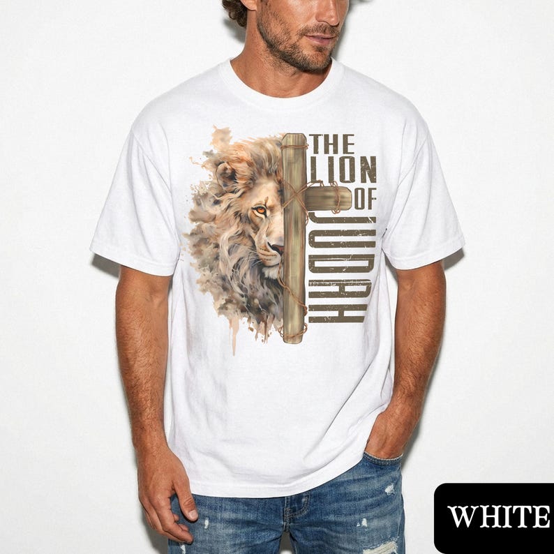 K&ouml;nnte beinhalten: Wei&szlig;es T-Shirt mit einem L&ouml;wenkopf- und Kreuz-Design. Der Text lautet "THE LION OF JUDAH". Die M&auml;hne des L&ouml;wen ist mit braunen und beigen Farbt&ouml;nen detailliert. Das Design ist auf ein wei&szlig;es T-Shirt gedruckt.