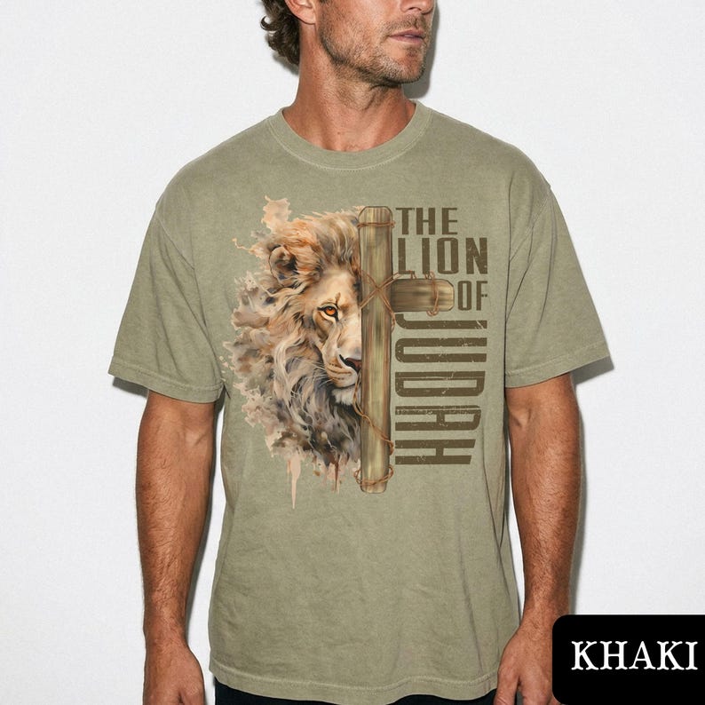 K&ouml;nnte beinhalten: Khaki-farbenes T-Shirt mit einer detaillierten Illustration eines L&ouml;wengesichts und eines Kreuzes. Der Text "THE LION OF JUDAH" ist auf das T-Shirt gedruckt. Das Shirt besteht aus einem weichen Material und hat kurze &Auml;rmel.