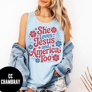 May include: Light blue tank top with the text "She Loves Jesus and America Too" in red and white. The design includes red and blue floral and star accents. The tank top is sleeveless.