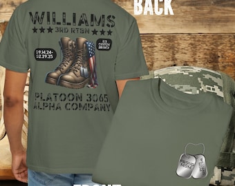 Könnte beinhalten: Grünes T-Shirt mit militärischem Thema. Die Rückseite des Shirts zeigt ein Design mit Stiefeln, einer amerikanischen Flagge und dem Text "WILLIAMS 3RD RTBN 09.14.24-02.29.25 PLATOON 3065 ALPHA COMPANY". Die Vorderseite des Shirts hat zwei Hundemarken mit dem Text "PROUD MOM" und "WILLIAMS MOM".
