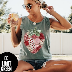 May include: Light green tank top with a large strawberry applique. The strawberry design is made of various fabric patterns, including gingham, floral, and polka dots. The text "CC LIGHT GREEN" is in a black circle.