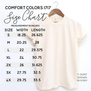 K&ouml;nnte beinhalten: Elfenbeinfarbenes T-Shirt auf einem Holzb&uuml;gel. Das Bild zeigt eine Gr&ouml;&szlig;entabelle mit Ma&szlig;en in Zoll f&uuml;r Breite und L&auml;nge, von Gr&ouml;&szlig;e S bis 4XL. Der Text enth&auml;lt "COMFORT COLORS 1717" und "Size Chart".