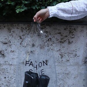 May include: A clear plastic bag with the words "Fashion Sole" printed on it. The bag contains two black shoe soles.