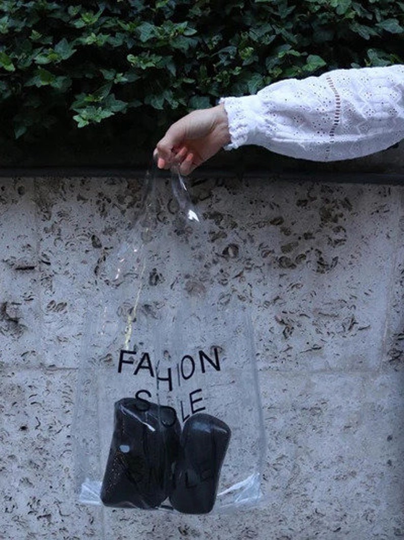 May include: A clear plastic bag with the words "Fashion Sole" printed on it. The bag contains two black shoe soles.
