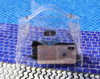 May include: A clear plastic handbag with a silver clasp and a silver handle. The bag is open and a gold iPhone is inside with the word "contents" written on the screen.