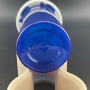 K&ouml;nnte beinhalten: Blaue Plastikflasche mit wei&szlig;em Deckel und dem Aufdruck "8-DR" auf dem Boden.
