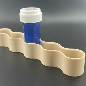 K&ouml;nnte beinhalten: Ein beigefarbener Plastik-Pillendose mit einer blauen Pillenflasche in einem der F&auml;cher.