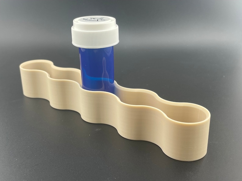 K&ouml;nnte beinhalten: Ein beigefarbener Plastik-Pillendose mit einer blauen Pillenflasche in einem der F&auml;cher.
