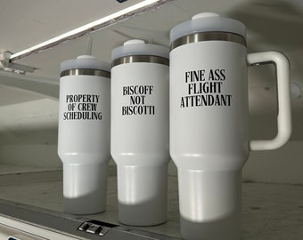 May include: Three white travel mugs with black text. The mugs are labelled "Property of Crew Scheduling", "Biscoff Not Biscotti", and "Fine Ass Flight Attendant".