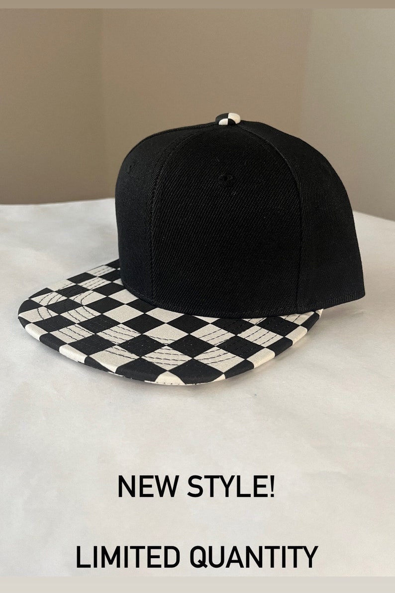May include: Black and white chequered baseball cap with a black crown. The text "NEW STYLE! LIMITED QUANTITY" is printed below the cap.