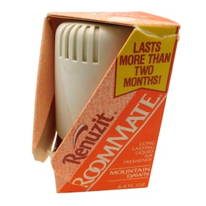 May include: A white air freshener in an orange and white box. The box reads "Renuzit ROOMMATE" and "MOUNTAIN DAWN". The box also states "LASTS MORE THAN TWO MONTHS!" and "4.4 FL OZ."
