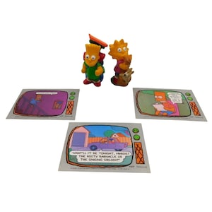 May include: A collection of Simpsons memorabilia featuring Bart and Lisa Simpson figurines, along with three cards depicting scenes from the show. The cards have text that reads "WHAT'LL IT BE TONIGHT, MARGE? THE RUSTY BARNACLE OR THE SINGING SIRLOIN?"