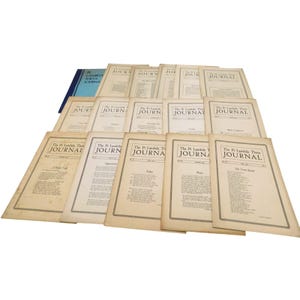May include: A collection of vintage journals, titled "The Pi Lambda Theta Journal," are arranged on a white surface. The journals have a cream-colored paper with black text and a blue journal in the background.