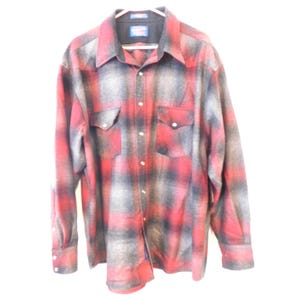 May include: A long-sleeve button-down shirt featuring a red and grey plaid pattern. The shirt includes a pointed collar, two chest pockets with button-down flaps, and a series of buttons running down the center front and on the sleeve cuffs.
