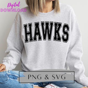 May include: A gray sweatshirt with the word "HAWKS" printed in black outlined letters. The sweatshirt is being worn by a person. The text "PNG & SVG FILES" is printed in white on a gray rectangle at the bottom of the image.