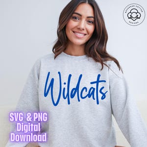 May include: Gray sweatshirt with the word "Wildcats" written in blue cursive lettering. The sweatshirt is a digital download available in SVG and PNG formats.