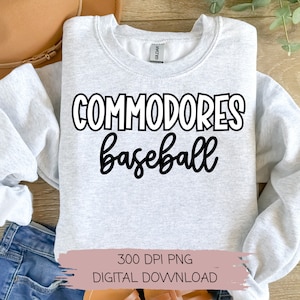 May include: A gray sweatshirt with the text "COMMODORES baseball" printed in black on the front. The sweatshirt is laying flat on a wooden surface.