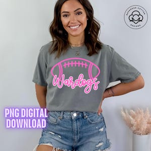 May include: Gray t-shirt with a pink football graphic and the word "Wardogs". The shirt is a digital download. The design includes a Backroad Cotton Designs logo.