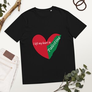 May include: Black t-shirt featuring a red and green heart design with the text "I left my heart in Palestine." The heart design incorporates the shape of Palestine. The shirt is made of a soft material.