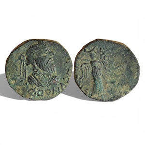 Puede incluir: Dos monedas antiguas de bronce. Una moneda presenta un busto barbudo y texto. La otra moneda muestra una figura con los brazos extendidos y un bastón. Las monedas tienen un aspecto envejecido y desgastado con tonos verdes y marrones.