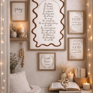 May include: A cozy, neutral-toned wall arrangement featuring framed inspirational quotes and artwork. The frames are in various sizes and shapes, with text that reads "pray", "be free", "Faith Hope Love", and "With God all things possible". Candles and decorative elements add warmth.