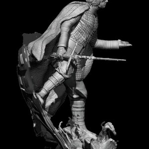 May include: A gray, detailed figurine of a character from a fantasy movie. The character is wearing a long cloak and holding a sword. The figurine is standing on a rocky base.