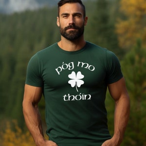 May include: A dark green t-shirt with a white four-leaf clover and the text "póg mo thóin" in white.