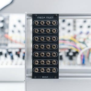 May include: A black electronic panel labeled "MEGA MULTI" with multiple input jacks. The panel is mounted on a silver frame. The text "BIGZUN" is printed at the bottom of the panel. The background is blurred, suggesting a focus on the panel.
