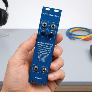 May include: A blue Attenuverter module with black knobs and silver jacks. The module has the text "ATTENUVERTER" repeated multiple times and "BIGZUN" at the bottom. Cables and headphones are visible in the background.