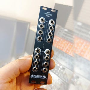 Op de afbeelding: Een zwart modulair synthesizerpaneel met het label 4x4 BUFFERED MULTI met twee kolommen van elk vier zilveren 3,5 mm jack-aansluitingen. Het paneel bevat witte tekst en afbeeldingen, waaronder de merknaam BIGZUN onderaan, en heeft montagegaten.