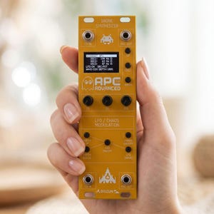 Könnte beinhalten: Ein senfgelbes Drone-Synthesizer-Modul mit einem digitalen Display, mehreren schwarzen Drehreglern sowie verschiedenen Ein- und Ausgangsbuchsen. Die Frontplatte ist mit weißem Text bedruckt, darunter "DRONE SYNTHESIZER", "APC ADVANCED" und "LFO / CHAOS MODULATION".