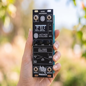 Può includere: Un modulo sintetizzatore drone Eurorack nero etichettato Aether Evolver. Il pannello frontale presenta un display digitale, tre manopole di controllo per Root, Harm e FM e una sezione per la modulazione LFO/Chaos con pulsanti e un grafico.