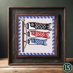 May include: Framed cross-stitch art featuring three colorful carp streamers, a traditional Japanese symbol. The carp are black, red, and blue, with intricate patterns. The artwork is set against a white background with a blue border, framed in a rustic wooden frame.
