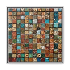 May include: A square framed artwork featuring a mosaic of small, textured squares. The squares are in a variety of colors including teal, orange, brown, and gold. The artwork has a white frame.