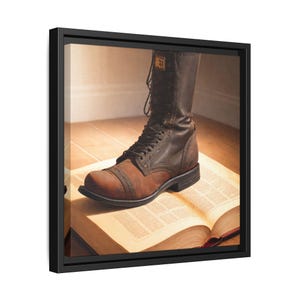 May include: A framed canvas print featuring a brown leather boot resting on an open book. The boot has a dark brown upper and a lighter brown toe cap. The book's pages are yellowed, and the background is a warm, neutral tone.