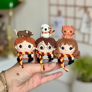 以下が含まれることがあります： かぎ針編みで作ったハリーポッターのキャラクターとその動物の仲間たち。キャラクターはハリーポッター、ロン・ウィーズリー、ハーマイオニー・グレンジャー。動物はヘドウィグのフクロウ、スカバースのネズミ、クロウクスハンクスの猫です。