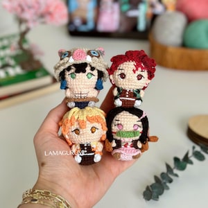 Może przedstawiać: Cztery małe, szydełkowe lalki postaci z anime. Lalki mają szczegółowe rysy twarzy i kolorowe stroje. Postacie obejmują lalkę z kapeluszem dzika, lalkę z rudymi włosami, lalkę z żółtymi włosami oraz lalkę z czarnymi włosami i różowym kimono.