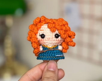 May include: A crocheted doll with orange hair, a blue dress, and brown eyes. The doll is holding a brown rope in its hands. The doll is about 3 inches tall.