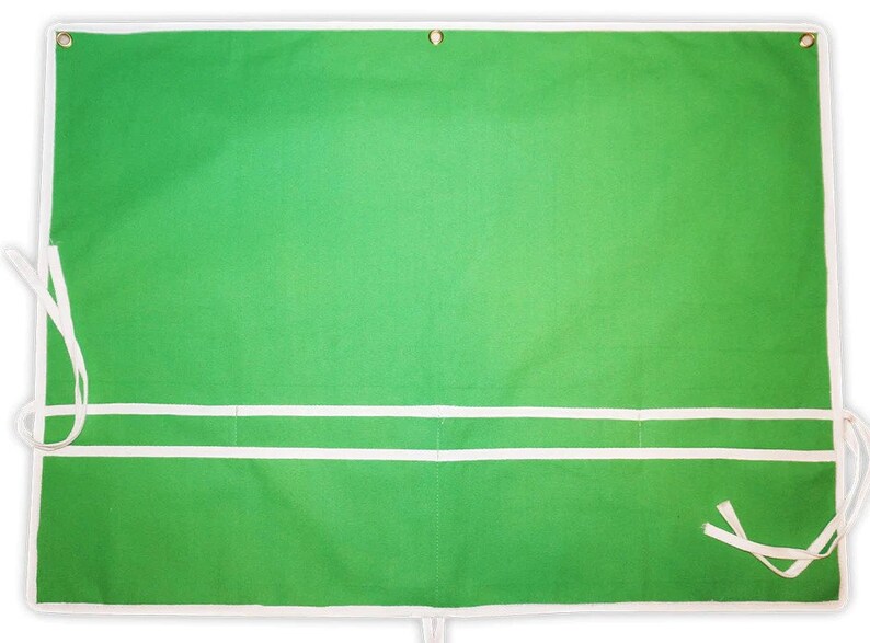 May include: Green canvas apron with two white pockets and white ties. The apron has a white border.