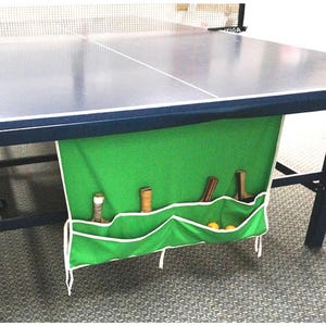 Durable 100% cotton ping pong table organizer for the Table Tennis aficionado. Available in Green, Blue, and Black, Ping Pong Pockets folds with your table! The under-mount design holds paddles, balls, and net in dedicated pockets for safe, accessible storage to keep gear organized and protected. Adhesive mounting or use the strings to tie it onto your table.