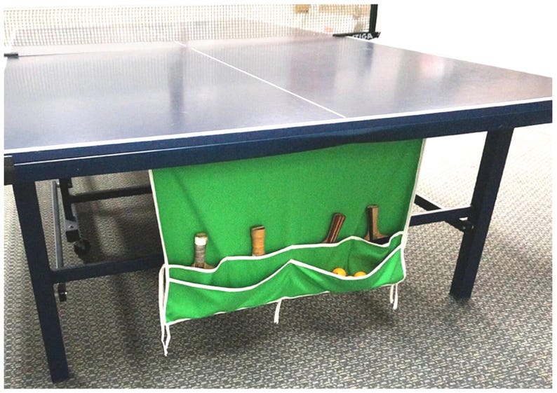 Durable 100% cotton ping pong table organizer for the Table Tennis aficionado. Available in Green, Blue, and Black, Ping Pong Pockets folds with your table! The under-mount design holds paddles, balls, and net in dedicated pockets for safe, accessible storage to keep gear organized and protected. Adhesive mounting or use the strings to tie it onto your table.