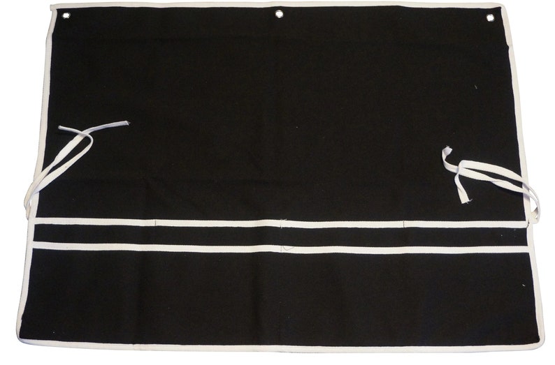 May include: Black canvas tool roll with white trim and two white straps. The roll has three pockets with white piping.