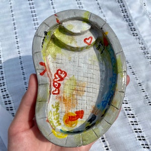 Piscina abandonada en miniatura con grafiti, plato de barro, bandeja para joyas y cenicero